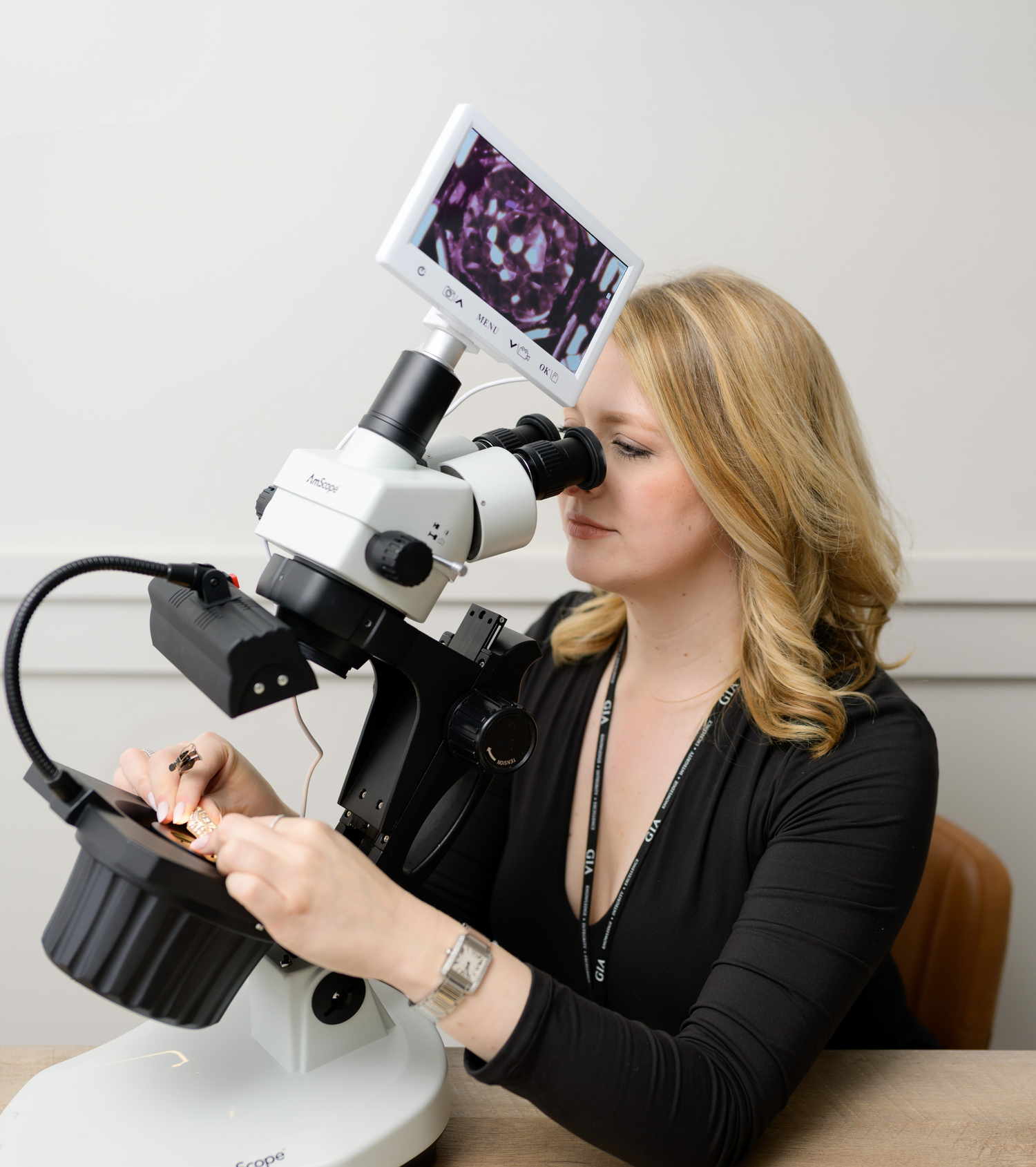 A professional gemologist at Devine Jeweler examining a diamond under a high-powered microscope. Experience expert gemstone evaluations and custom fine jewelry at www.devinejeweler.com.