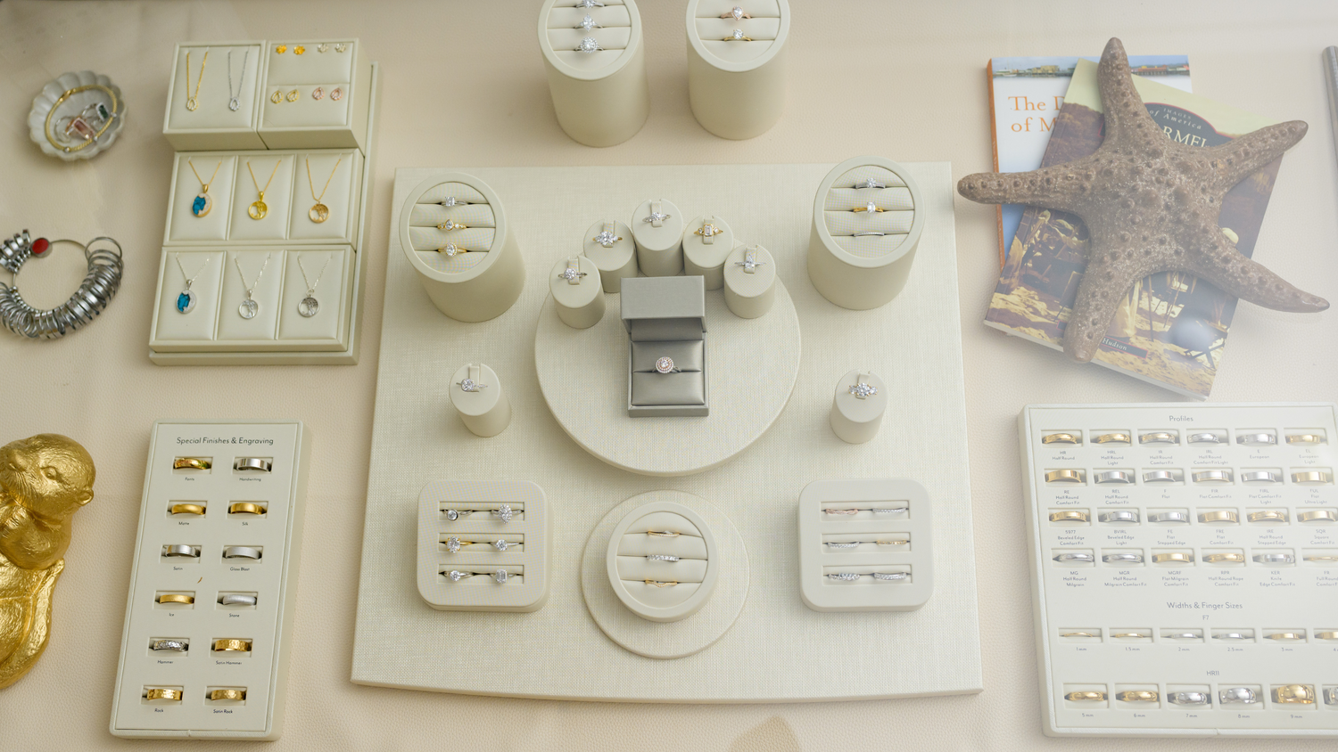 Elegant jewelry display featuring gold and silver rings, necklaces, and gemstone pieces. Explore timeless designs at Devine Jeweler.