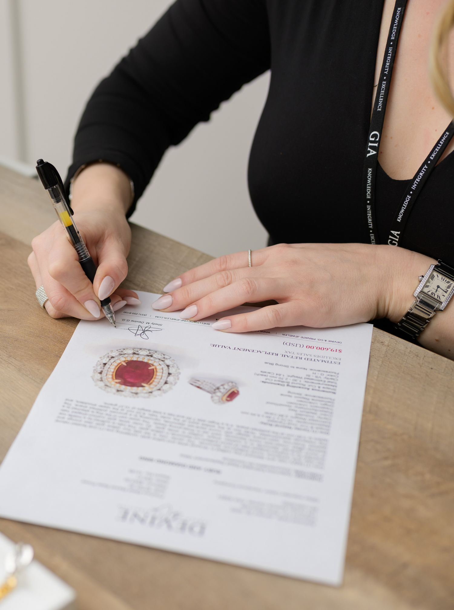 A certified gemologist at Devine Jeweler carefully evaluating and documenting a stunning ruby and diamond ring appraisal.