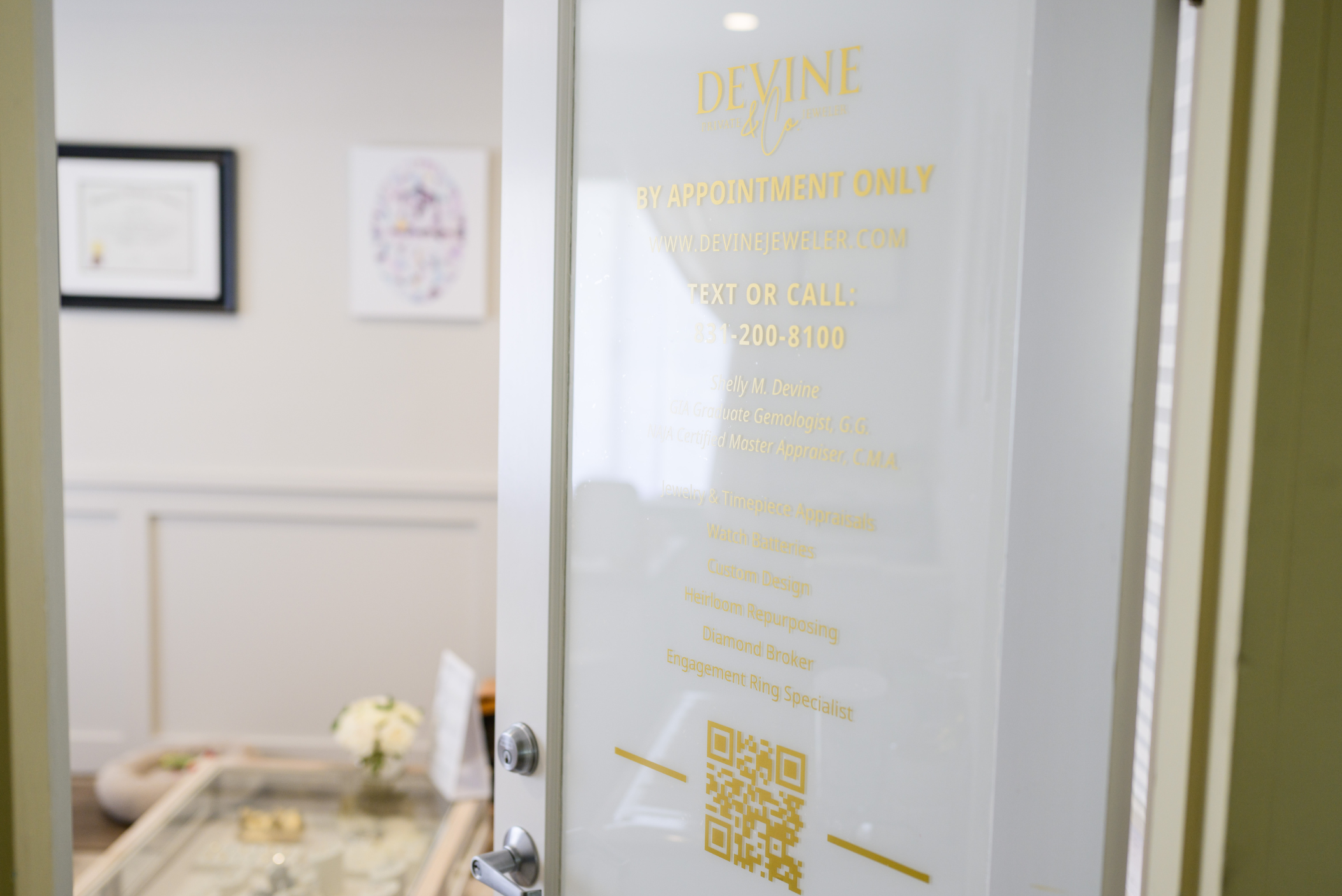 The entrance to Devine Jeweler, featuring elegant gold lettering on a glass door, highlighting expert jewelry appraisals, custom designs, and diamond brokerage services.