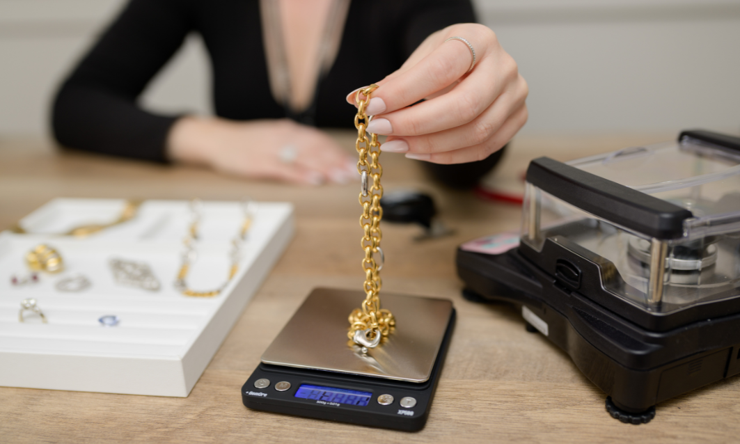 Gold jewelry being weighed on a digital scale for quality and authenticity. Explore premium gold and silver pieces at Devine Jeweler.